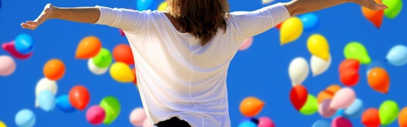 Self-confidence - woman looking at the sky filled with colored balloons