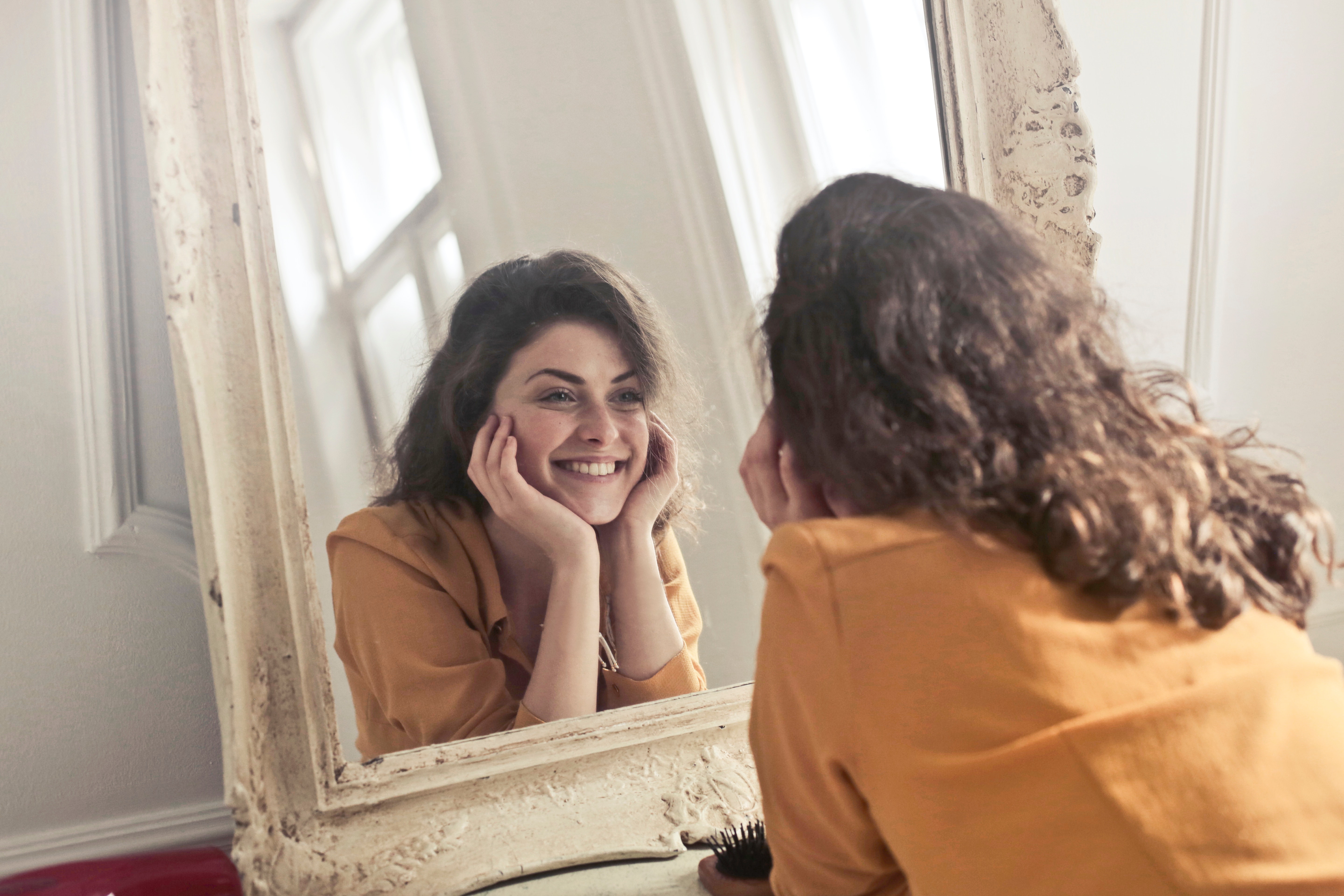 Woman looking at the mirror and smiling happily - No matter what the world says, its ok to live your life